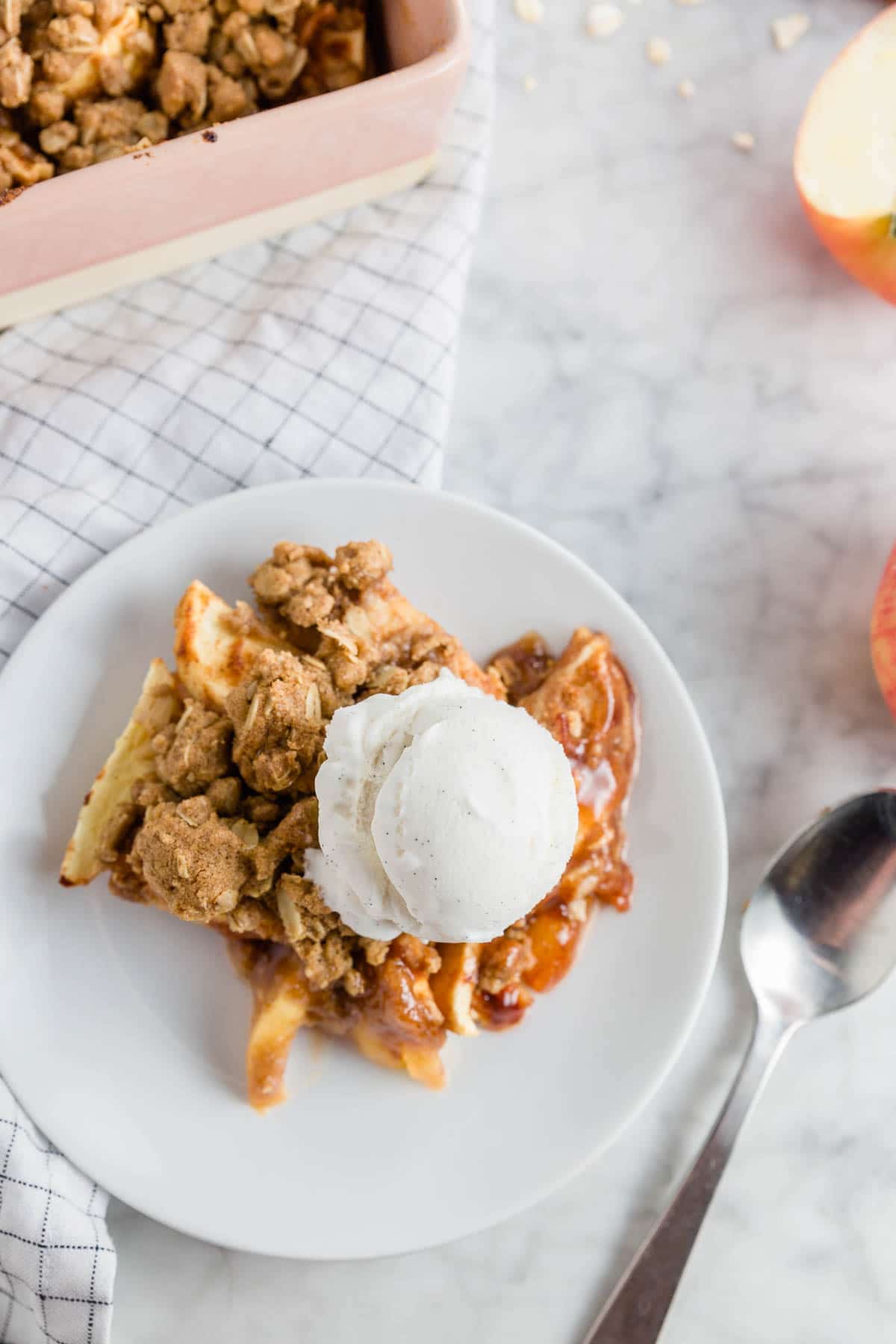 A white plate with gluten-free apple crisp and a scoop of vanilla bean ice cream. 