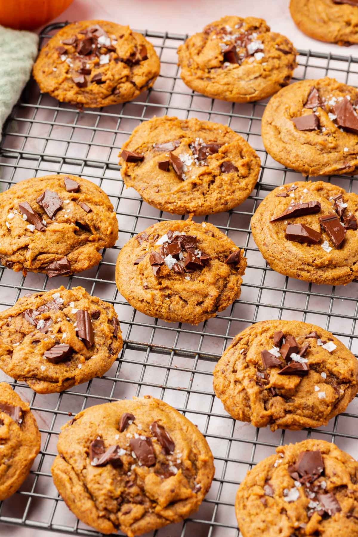 A cooling rack filled with gluten-free pumpkin chocolate chunk cookies topped with flaky sea salt.