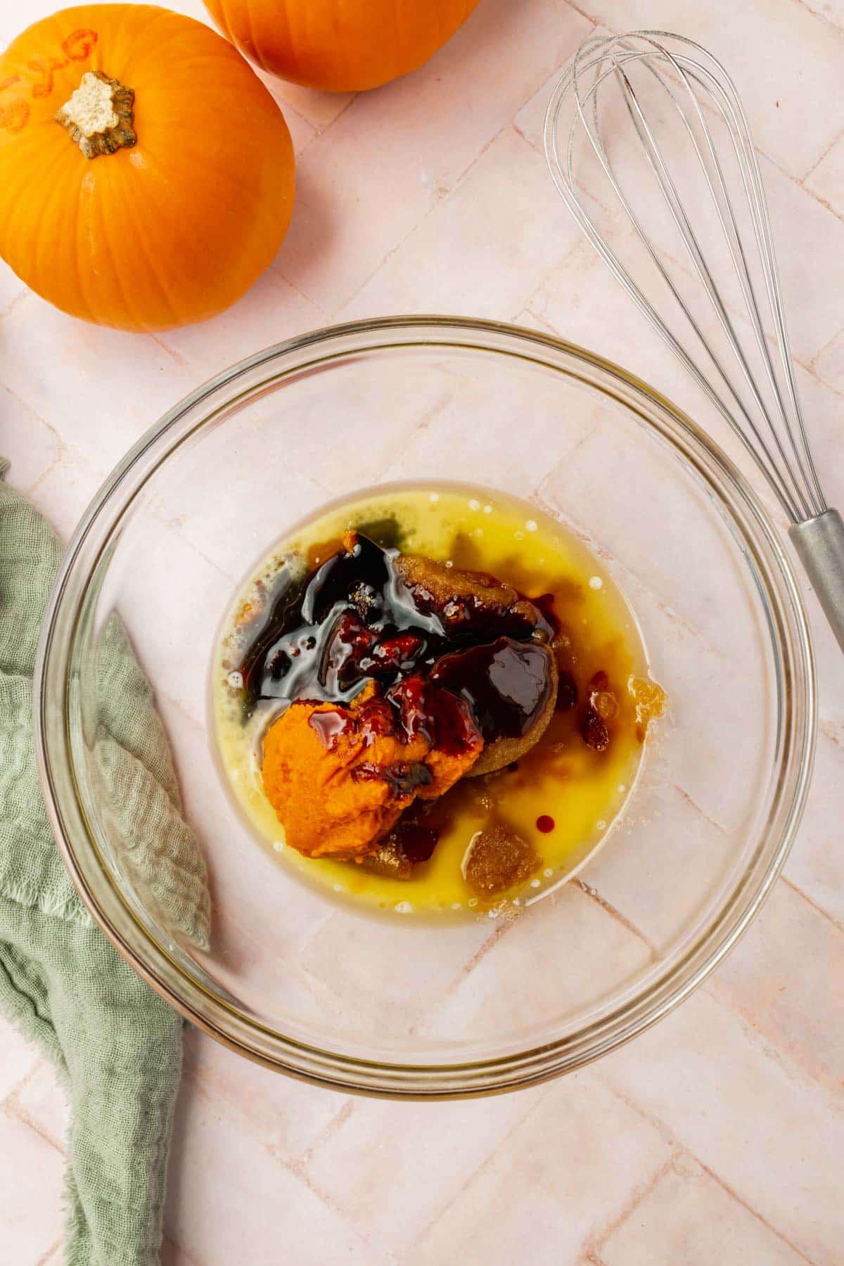 A glass mixing bowl with melted butter, pumpkin puree, brown sugar, molasses, and vanilla extract before mixing.