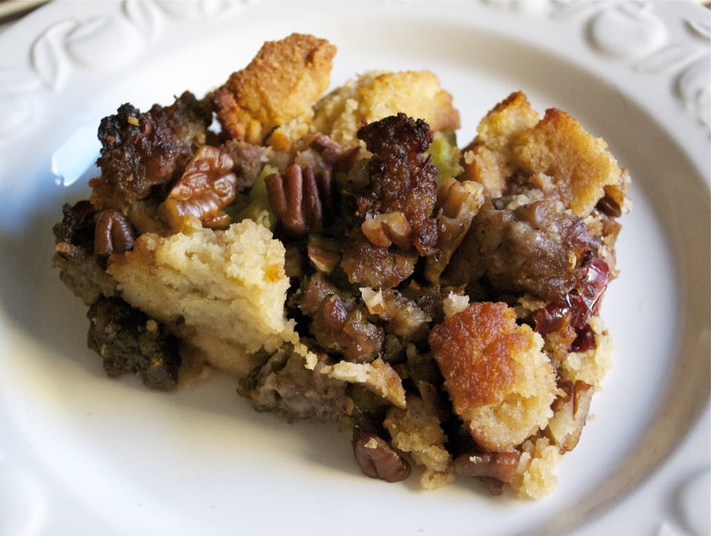 A slice of gluten-free cornbread stuffing topped with sausage and pecans.
