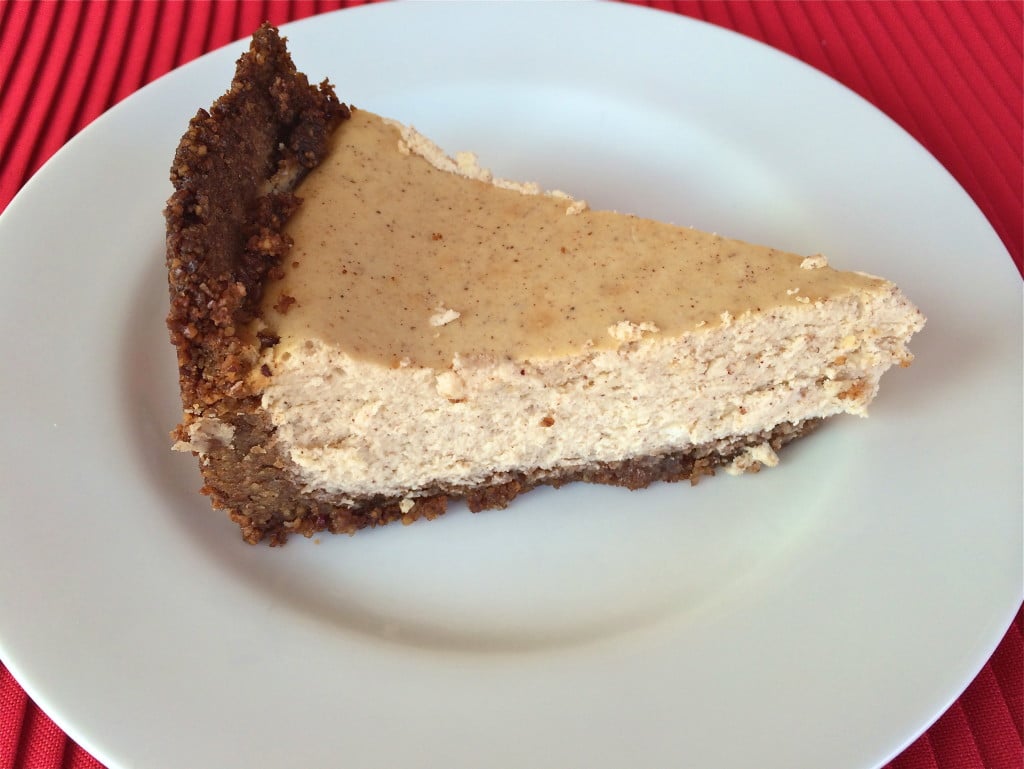 A slice of pumpkin spice pie with pecan crust on a white plate.