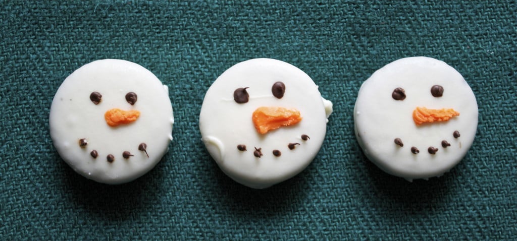 White chocolate dipped oreos decorated like snowmen faces.