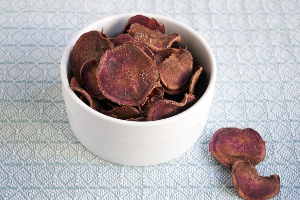 A ramekin of baked purple sweet potato chips topped with salt.