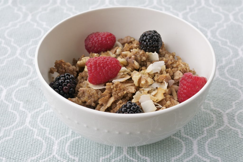 A bowl of baked quinoa topped with walnuts, toasted coconut, raspberries, and blackberries. 
