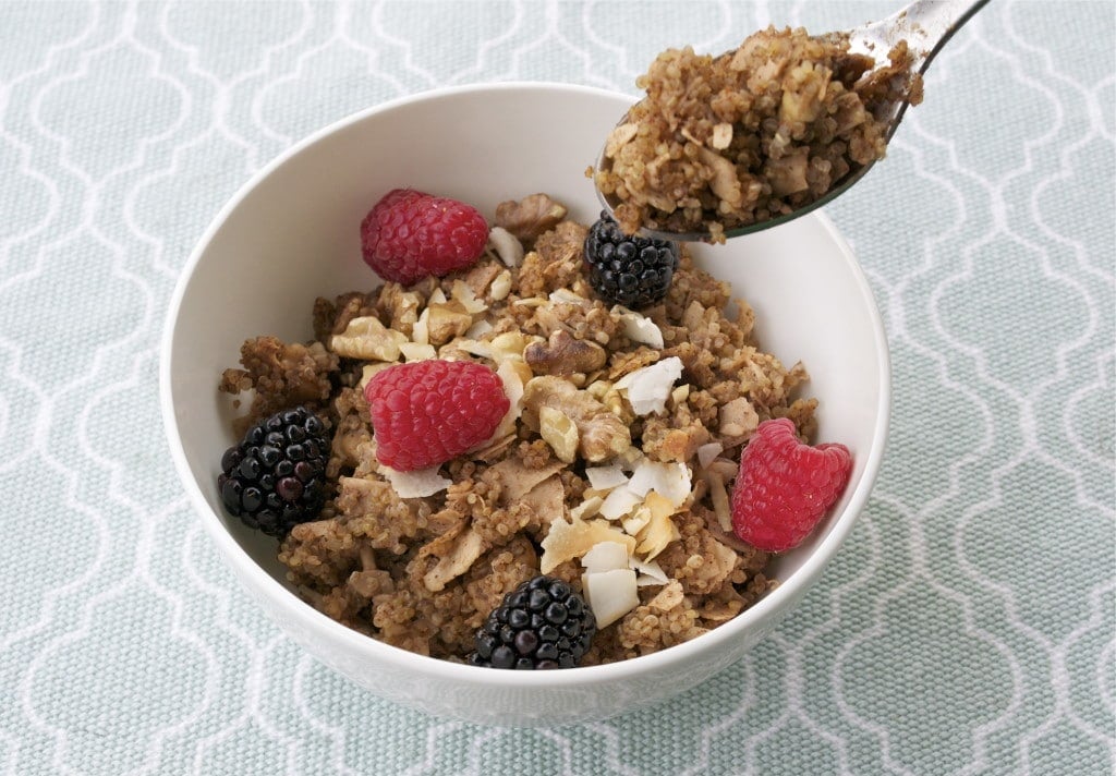 A bowl of baked quinoa topped with blackberries, raspberries and toasted coconut.
