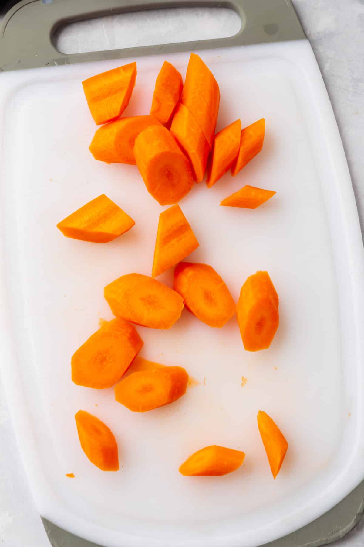 Carrots sliced on the bias on a white cutting board.