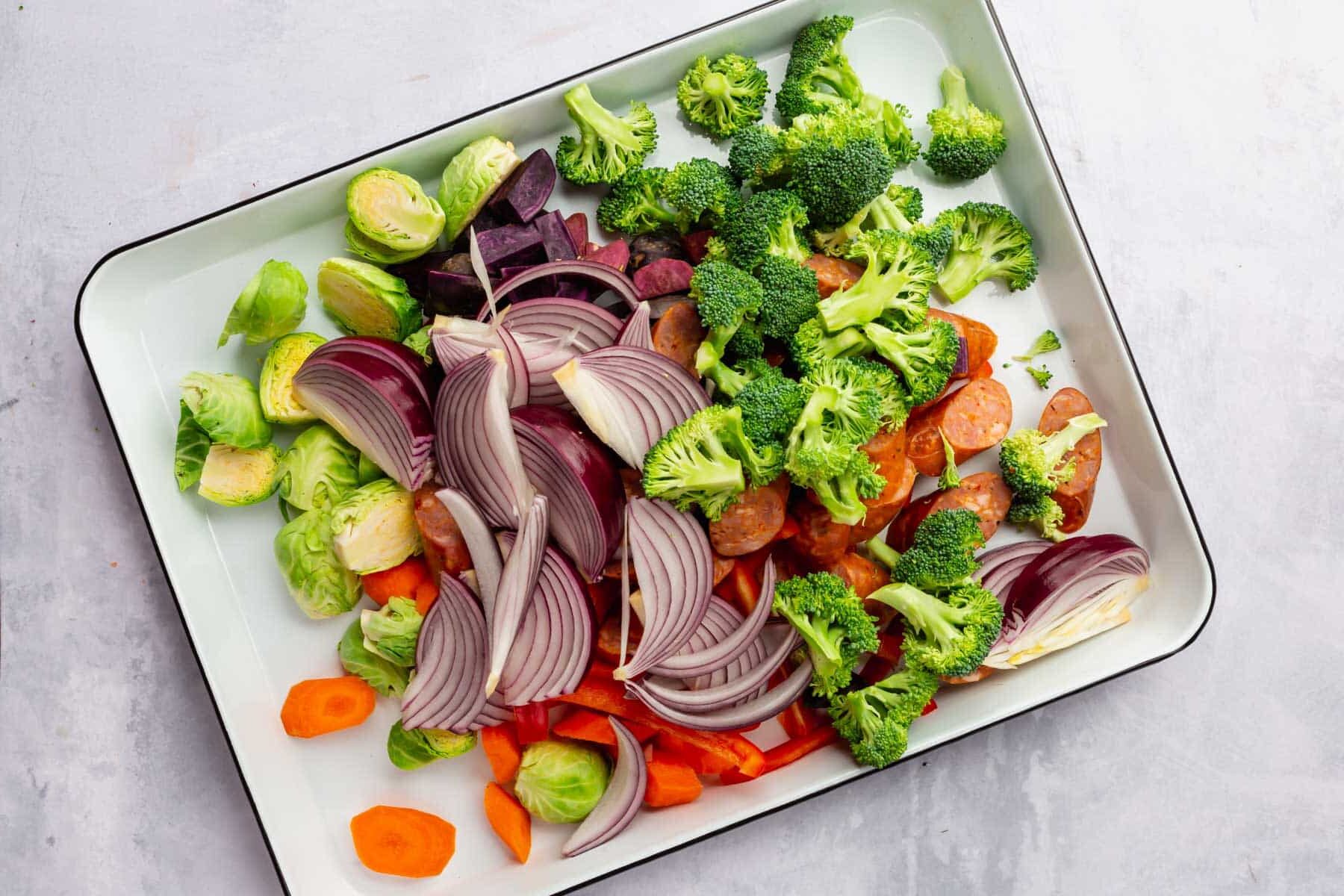 Raw vegetables combined on a sheet pan before baking.