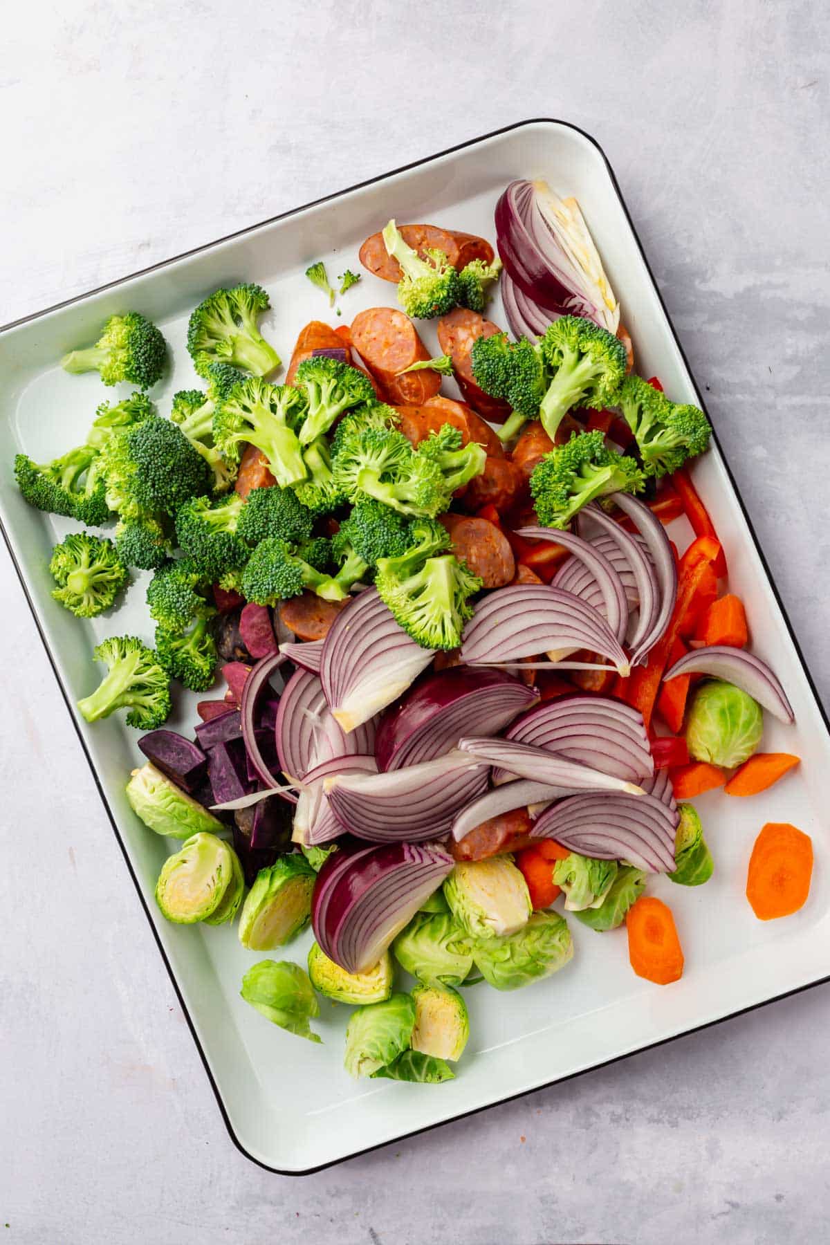 Raw vegetables combined on a sheet pan before baking.