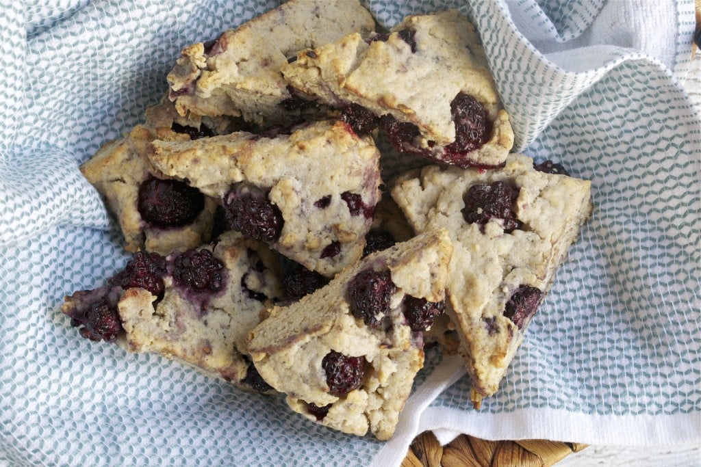 A basket lined with a kitchen towel and filled with a pile of blackberry scones.