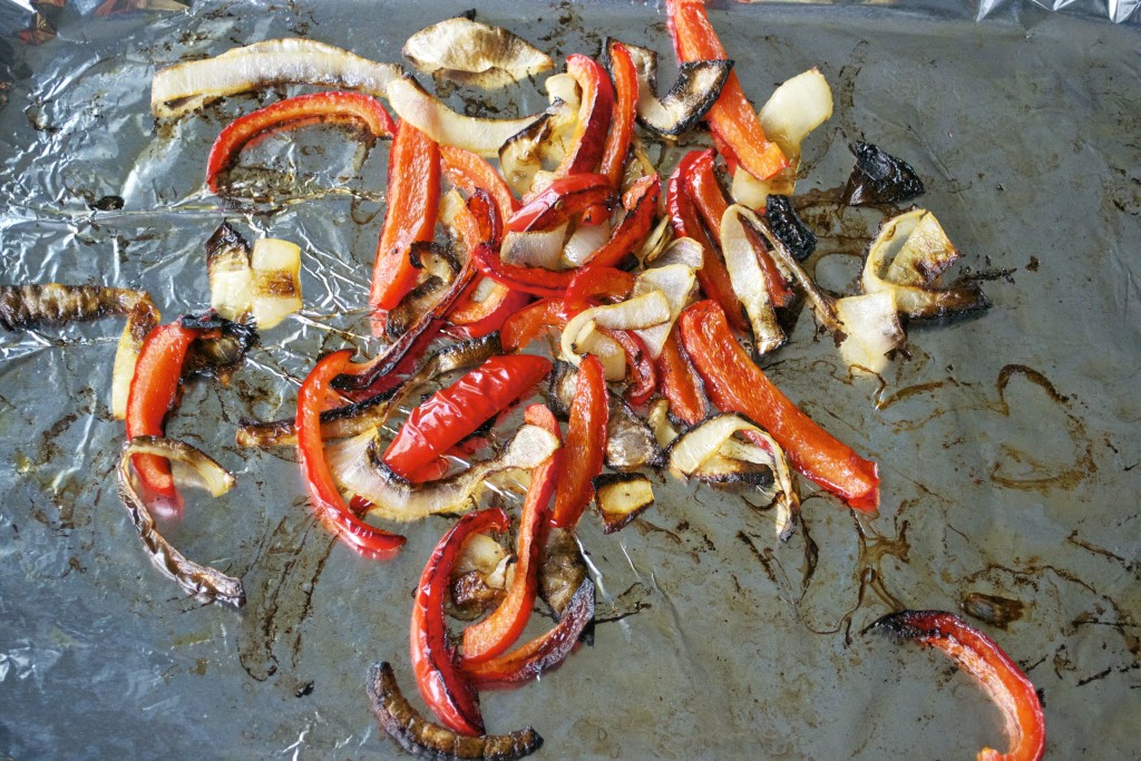 Roasted onion and bell pepper on a baking sheet lined with aluminum foil.