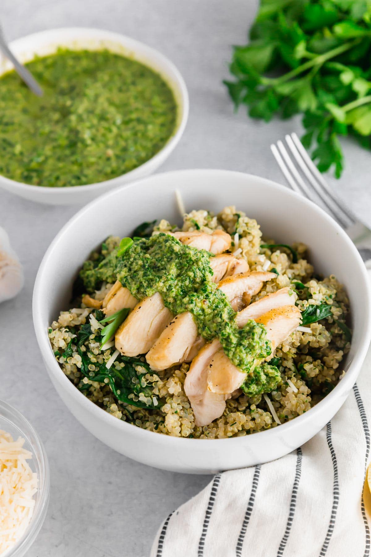 A photo of of a bowl with quinoa and chicken topped with homemade vegan parsley walnut pesto.