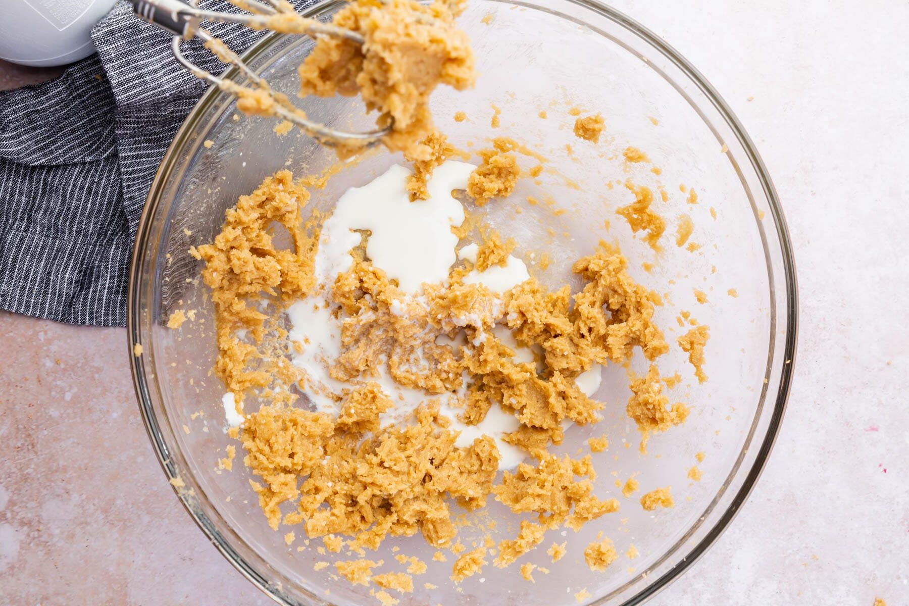 A bowl of milk, salt, vanilla and creamed butter and sugar.