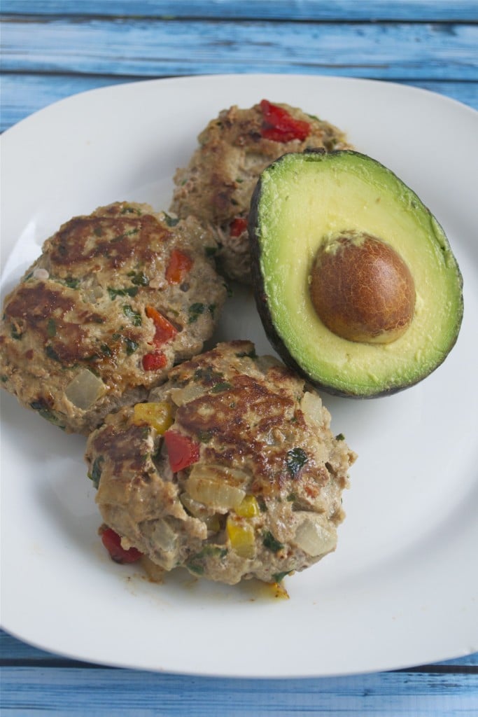 A plate of three turkey veggie burgers with an avocado half.