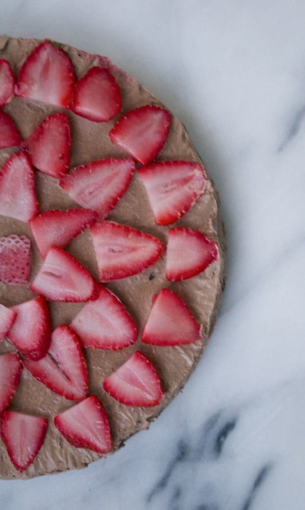 A vegan chocolate cheesecake topped with strawberry slices. 