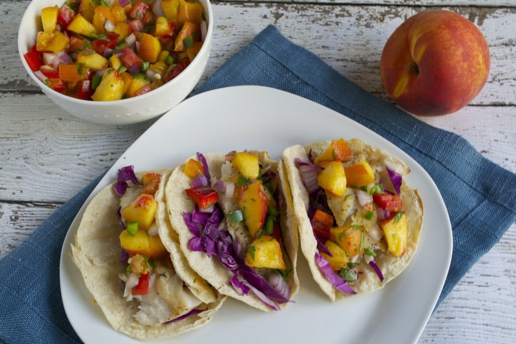 A plate of three tilapia tacos with peach salsa and red cabbage. 