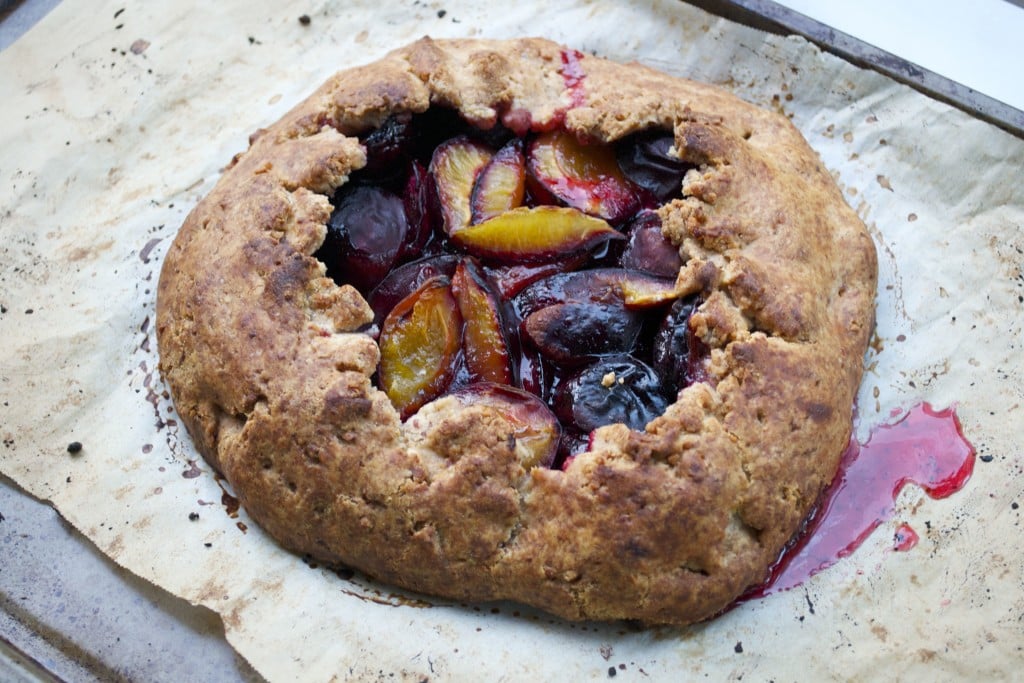 A plum galette on a baking sheet lined with parchment paper.