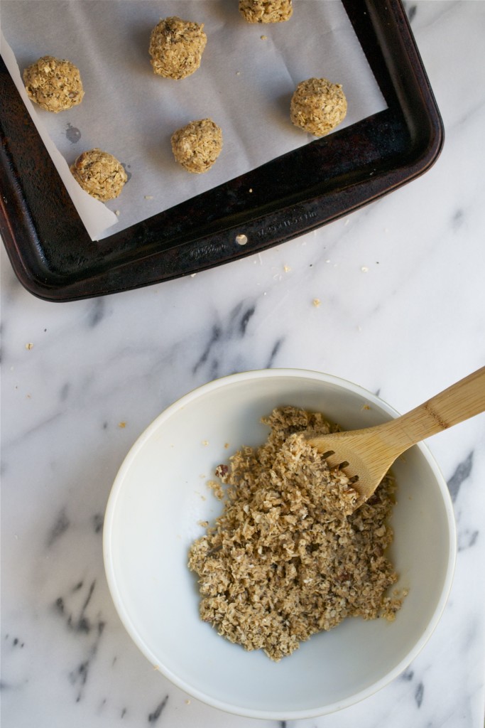 A bowl of oats next to a baking sheet with chai coconut date bites on it.