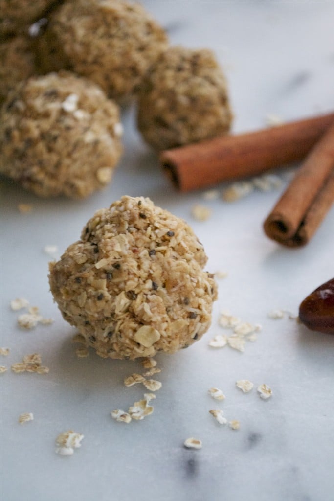 A chai date energy ball in front of cinnamon sticks.