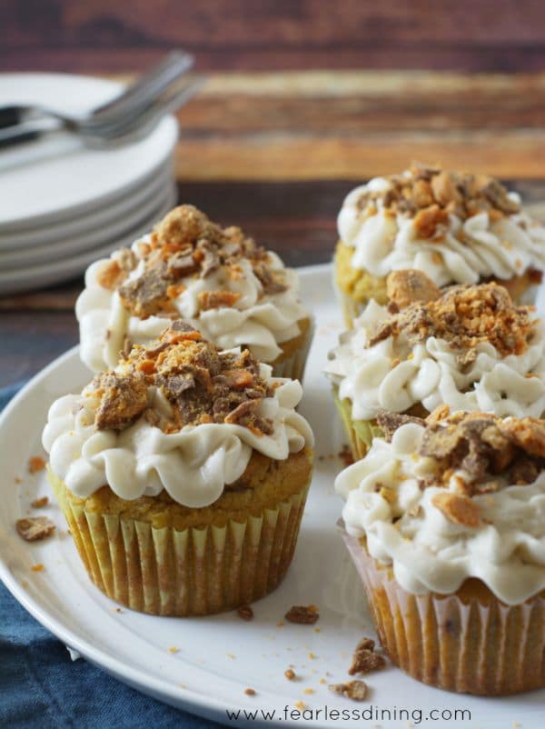 A plate with pumpkin butterfinger cupcakes with buttercream and crushed butterfingers on it.
