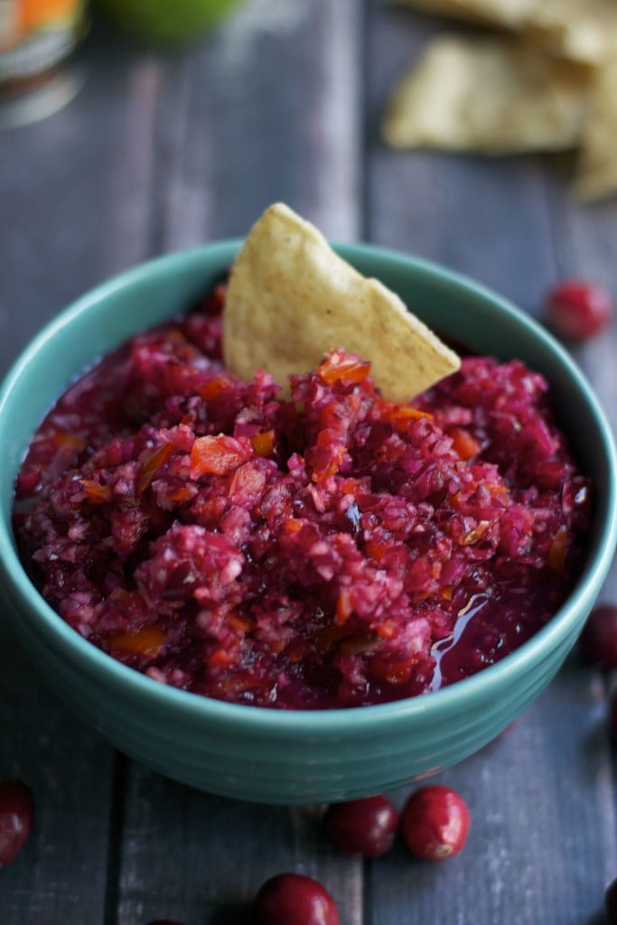 A bowl of cranberry jalapeño salsa with a tortilla chip in it.