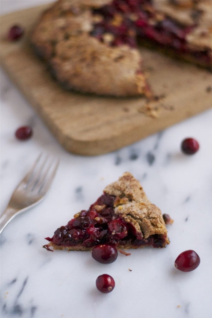 A slice of cranberry galette in front of a serving board with the rest of the galette.