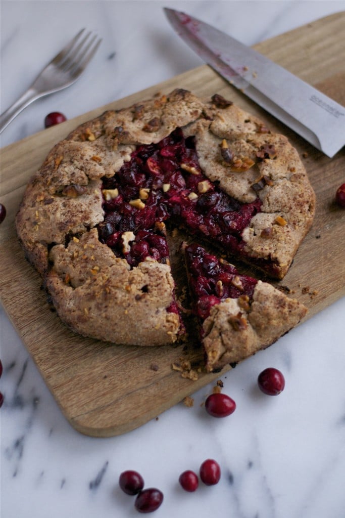 A cranberry rosemary galette on a serving board with a slice cut out of it.