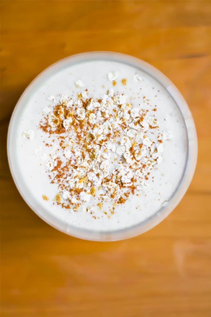 An overhead view of a glass of ginger pear smoothie topped with oats and cinnamon.