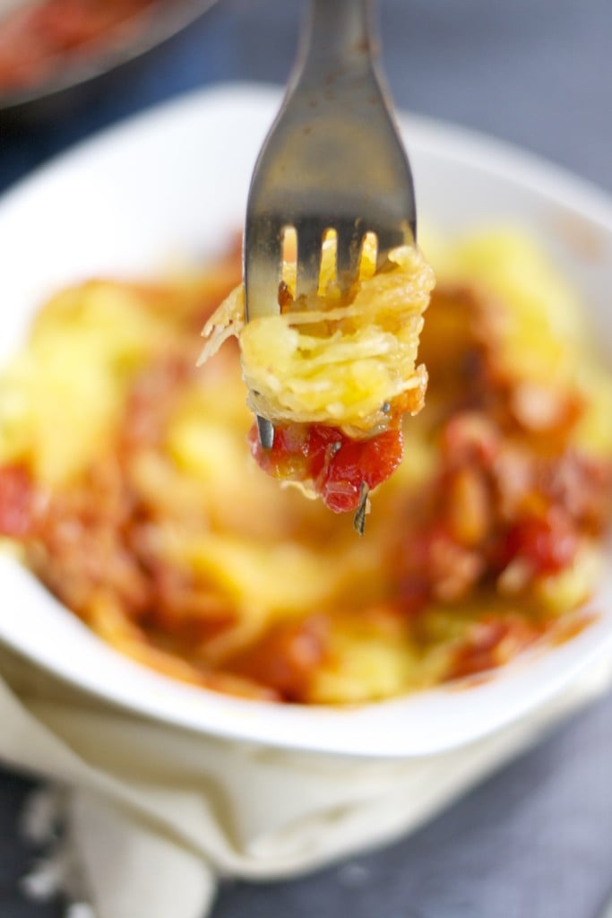 A fork twirling spaghetti squash and topped with tomato sauce.