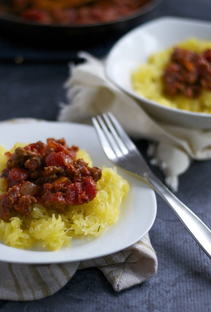 A plate of spaghetti squash topped with meat sauce with a fork on the side.