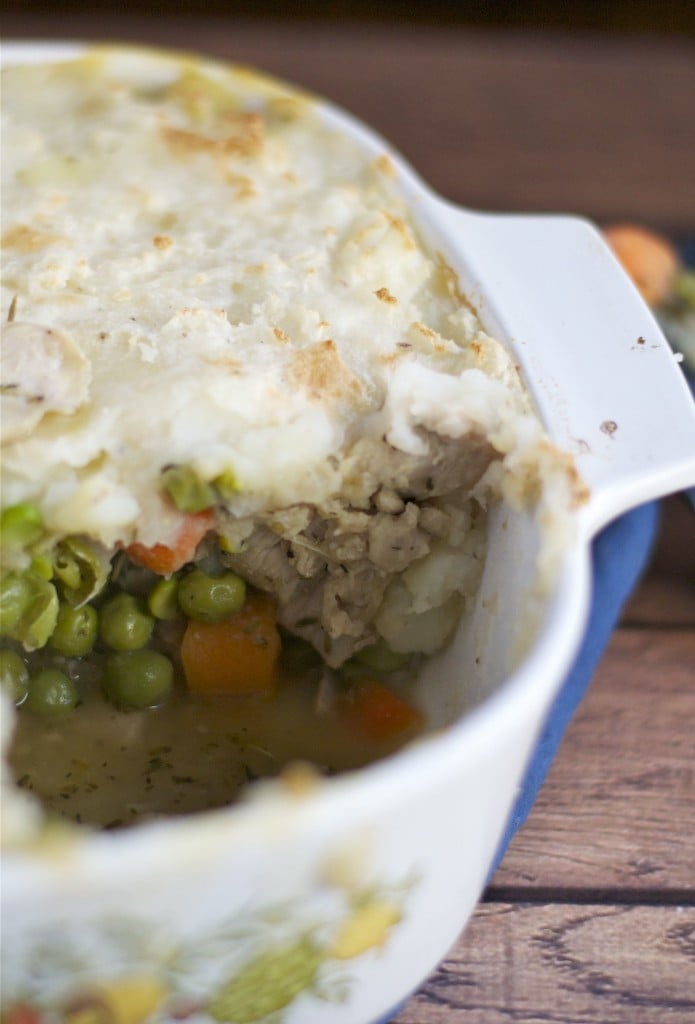 A casserole dish of turkey shepherd's pie with peas and carrots in it and topped with mashed potatoes. 