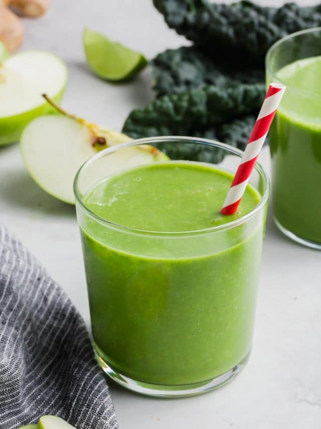 A glass of apple and kale smoothie with a straw.