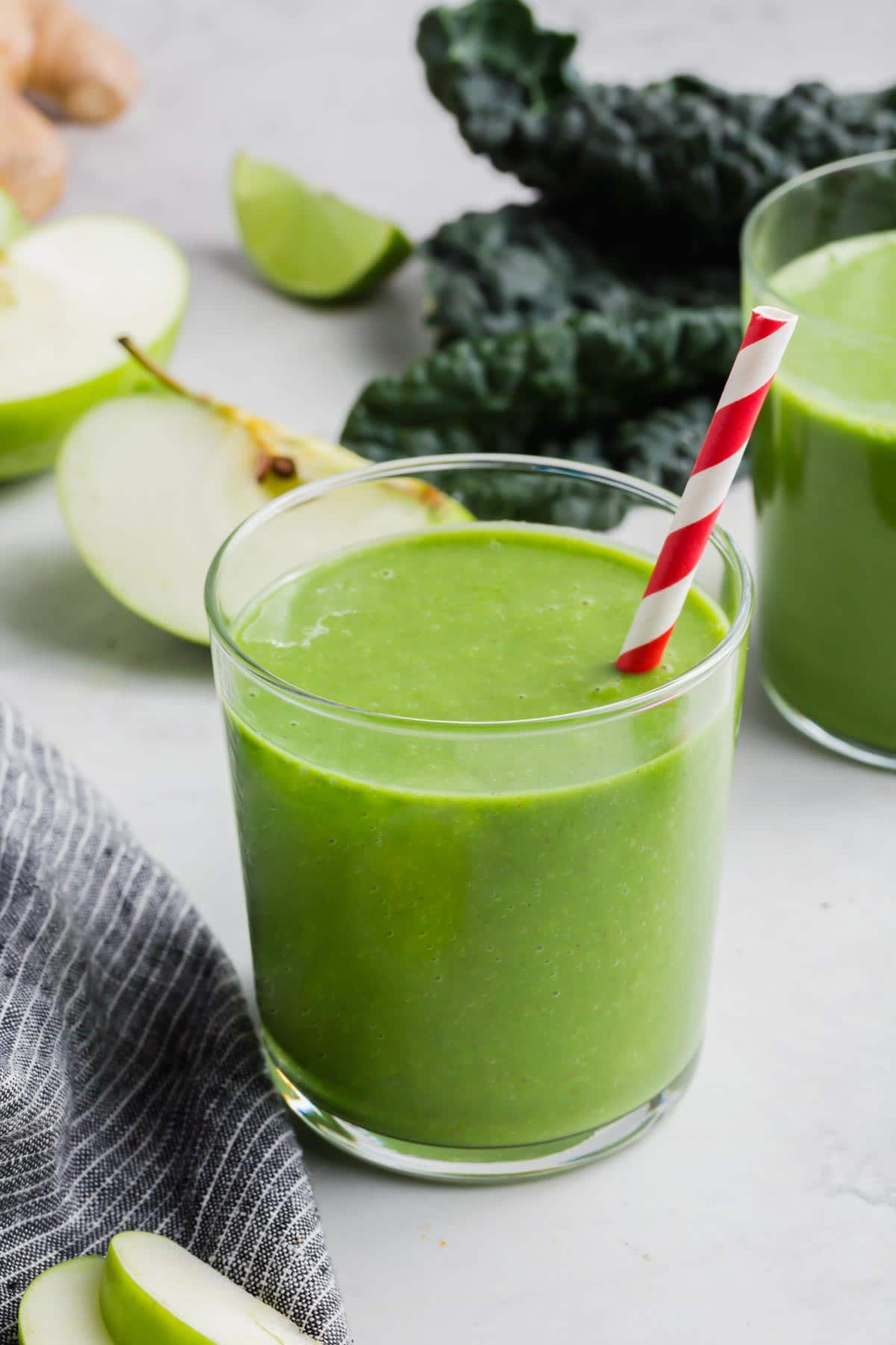 A glass of apple and kale smoothie with a straw.