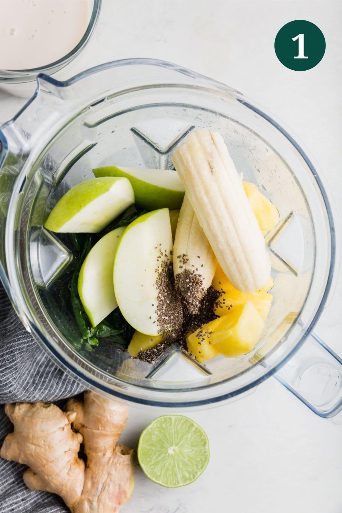 A blender with banana, apple, chia seeds, and pineapple.