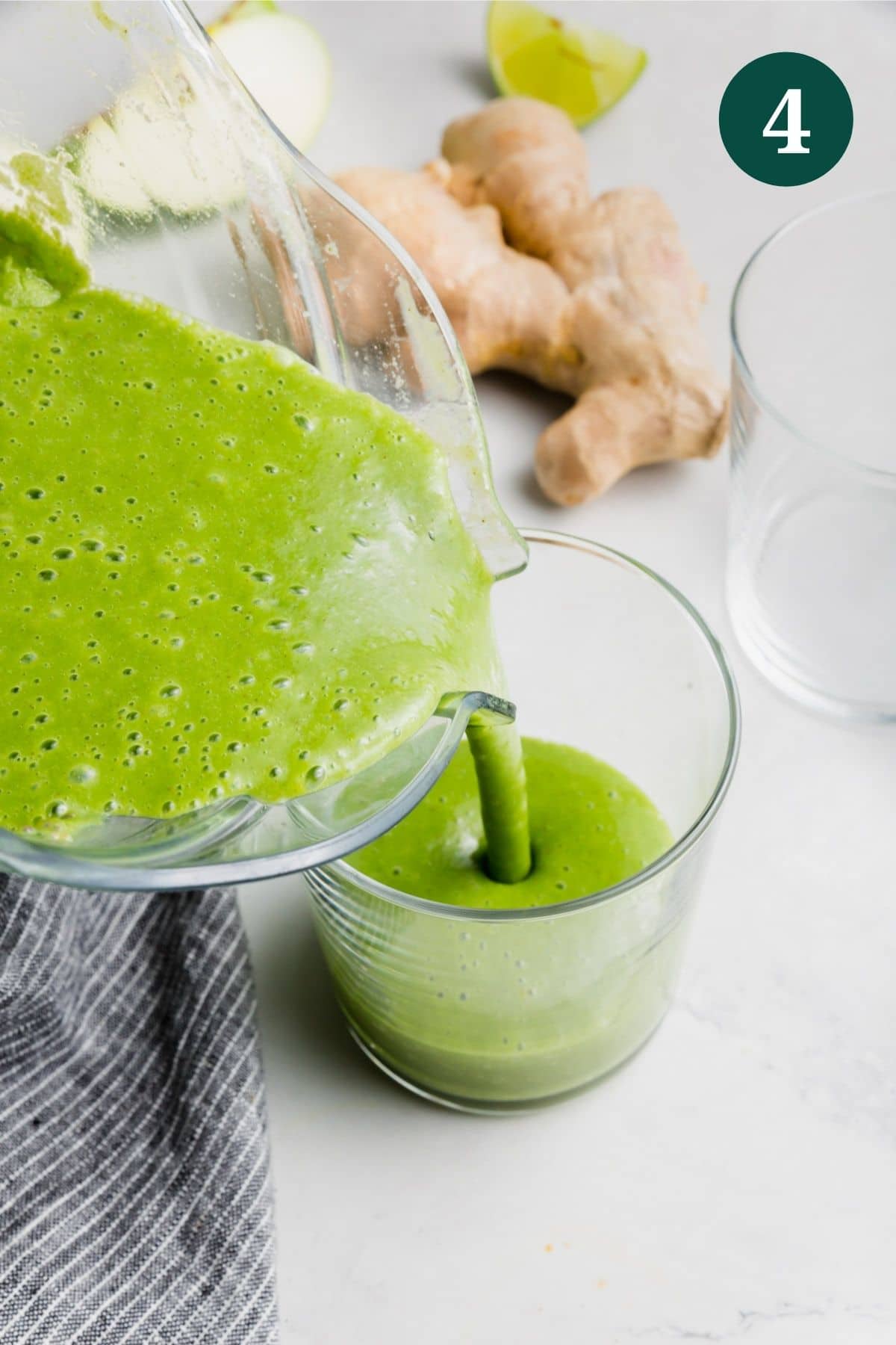 An apple kale green smoothie being poured into a glass.