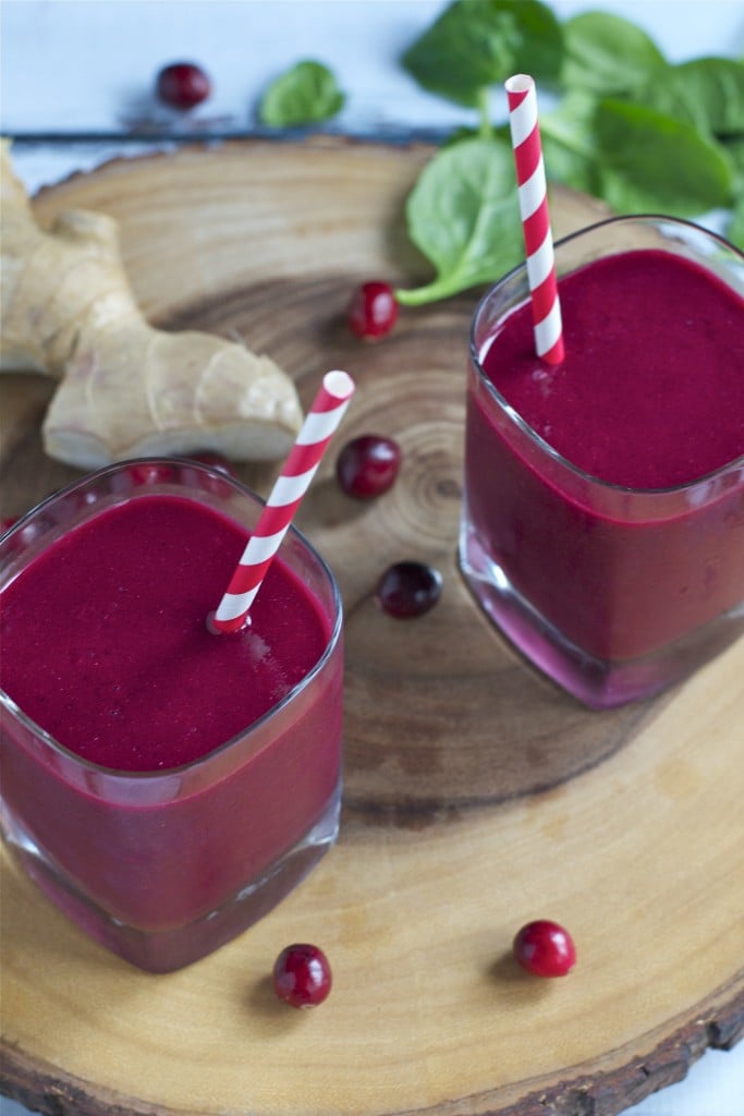 Two glasses of cranberry beet smoothie with red and white striped straws.