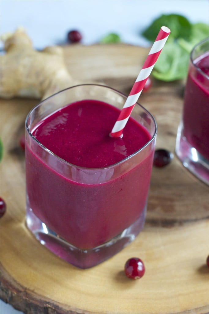 A glass of cranberry beet smoothie with a striped straw. 