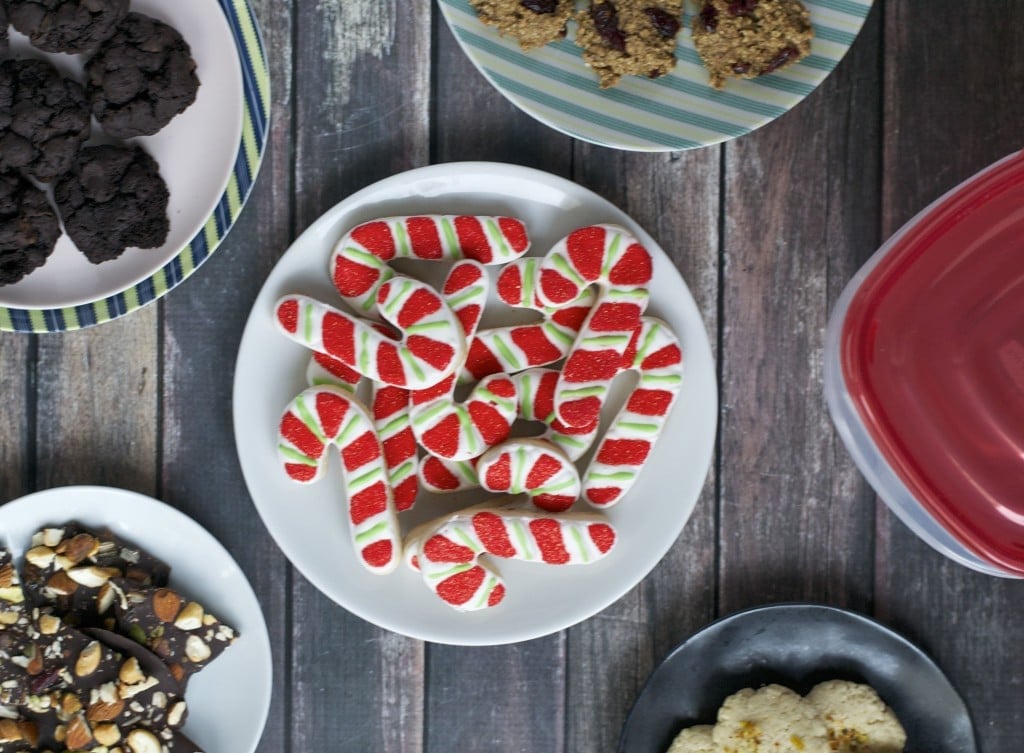 An overhead view of an assortment of cookies on different plates including candy cane cookies.