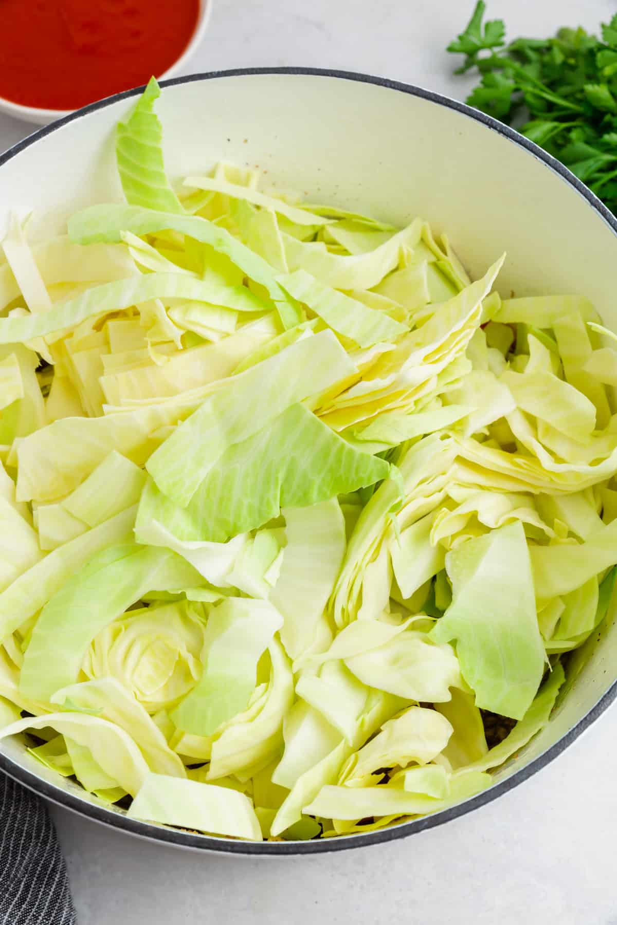 A white dutch oven of shredded cabbage.