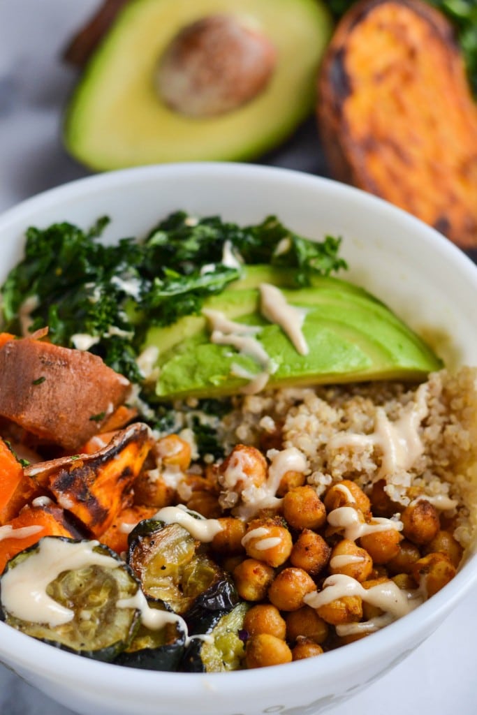 A bowl of Curried Chickpea and Sweet Potato Quinoa power bowl topped with avocado, zucchini and kale.