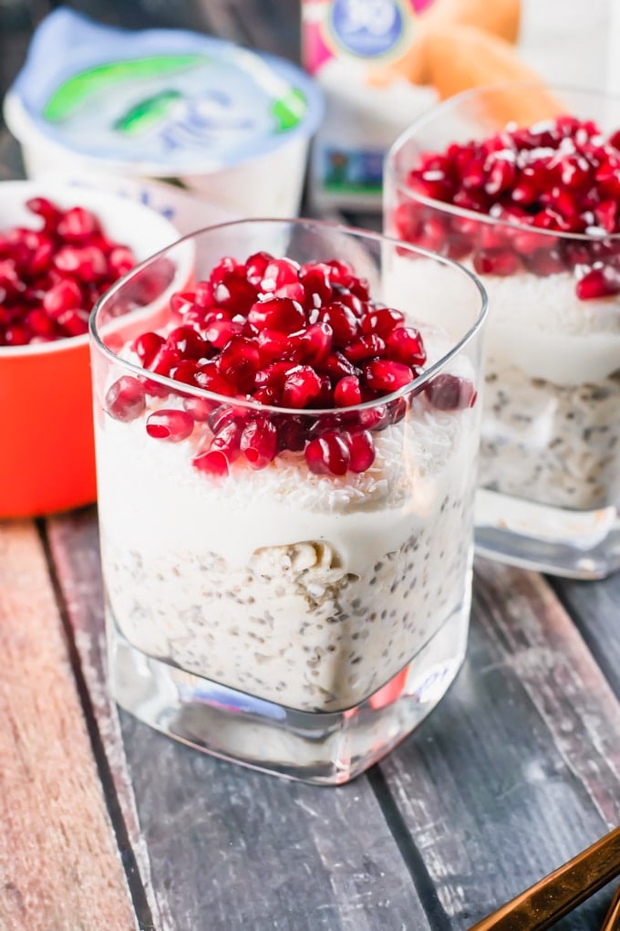 A glass of overnight oats topped with yogurt and pomegranate arils.