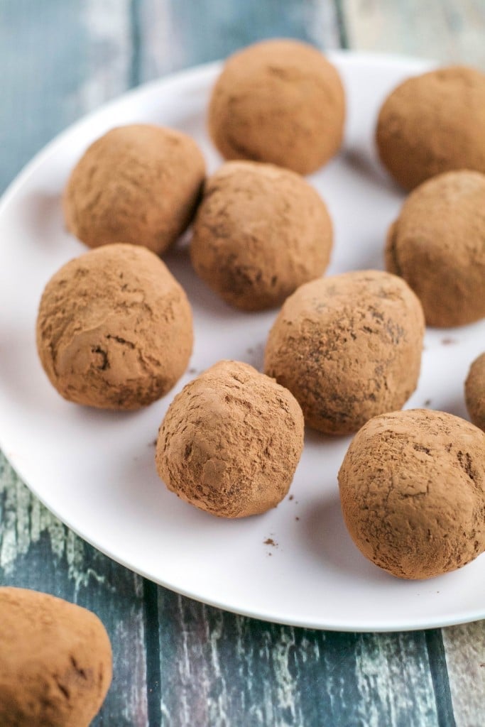 Chocolate truffles rolled in cocoa powder on a white plate.