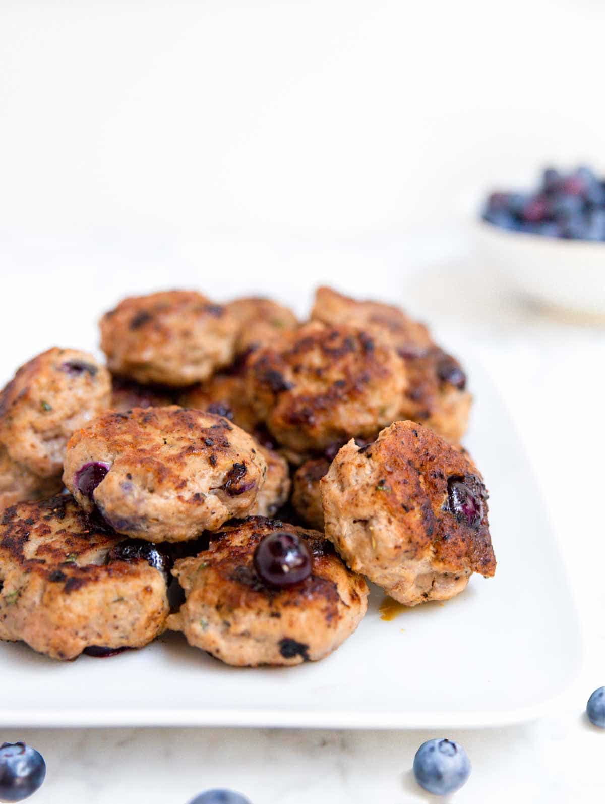 A white platter topped with blueberry turkey breakfast sausage and fresh blueberries. 