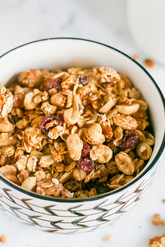 A bowl of granola with peanuts and dried cranberries on top. 