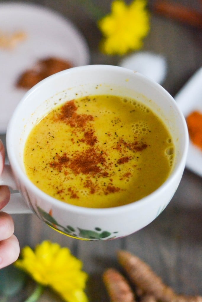 A mug of a hot golden milk latte topped with cinnamon and turmeric.