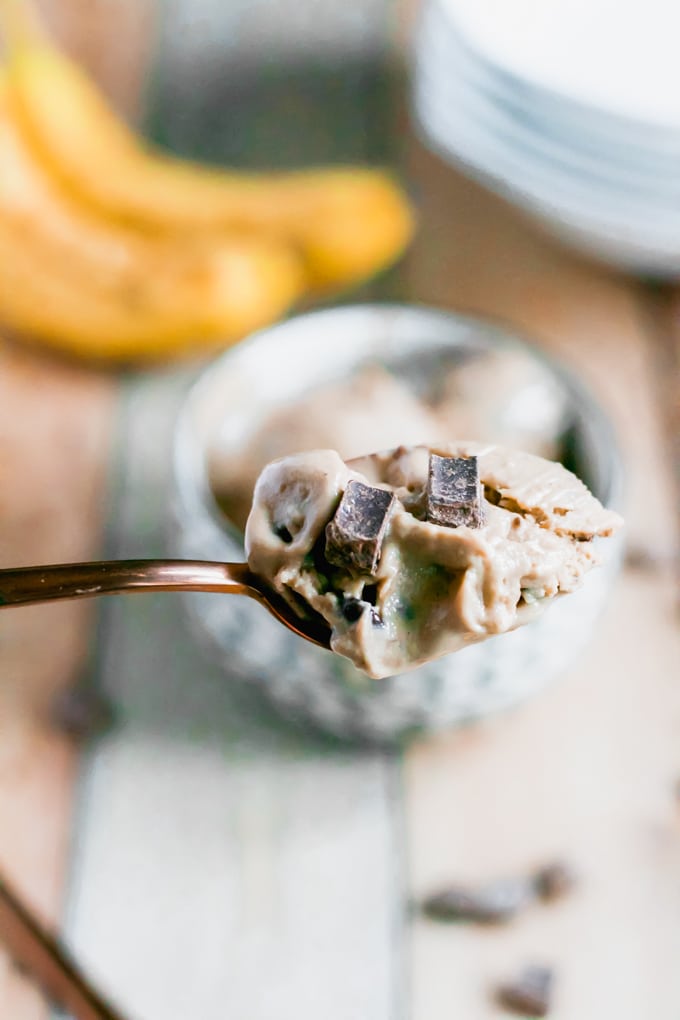 A spoon full of vegan banana ice cream with chocolate chunks on top. 