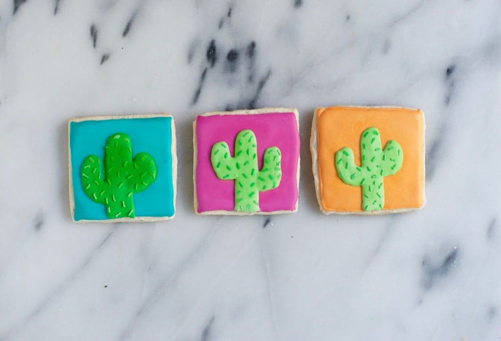 Three Gluten-Free Cactus Sugar Cookies on a marble table.