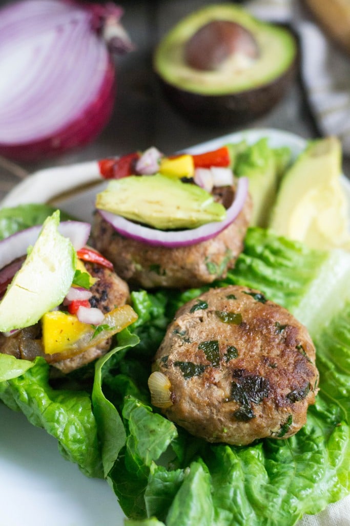 A lettuce wrap with spinach garlic turkey burgers topped with sliced avocado and mango salsa. 