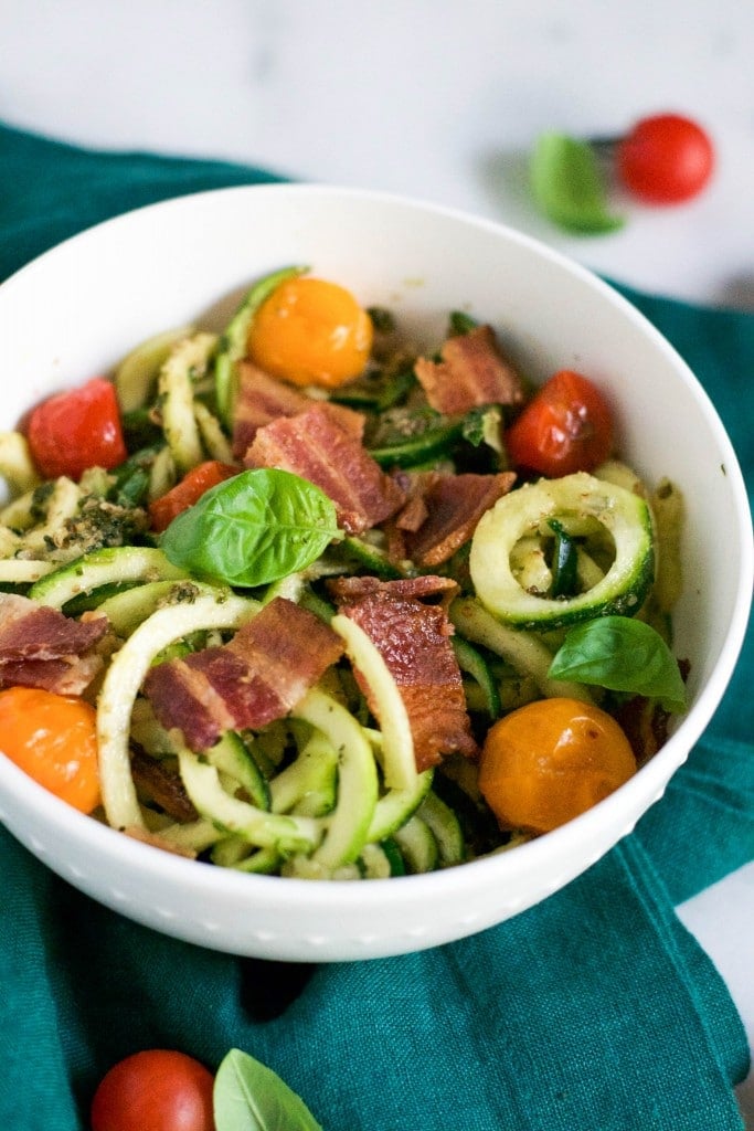 A bowl of zucchini noodles with basil, bacon and cherry tomatoes. 