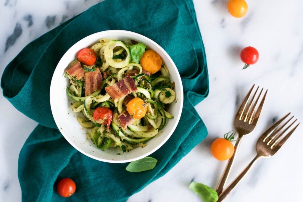 A bowl of zucchini noodles with bacon, cherry tomatoes and basil. 