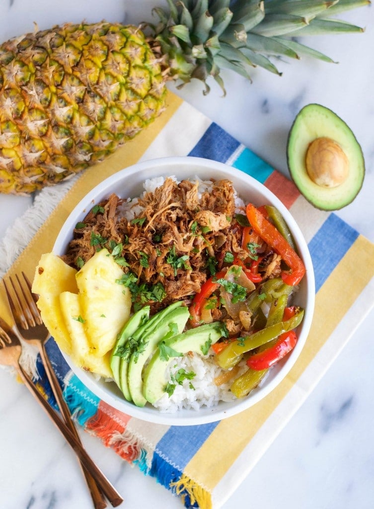 A bowl of pineapple pork burrito bowl with rice, avocado, and roasted peppers. 